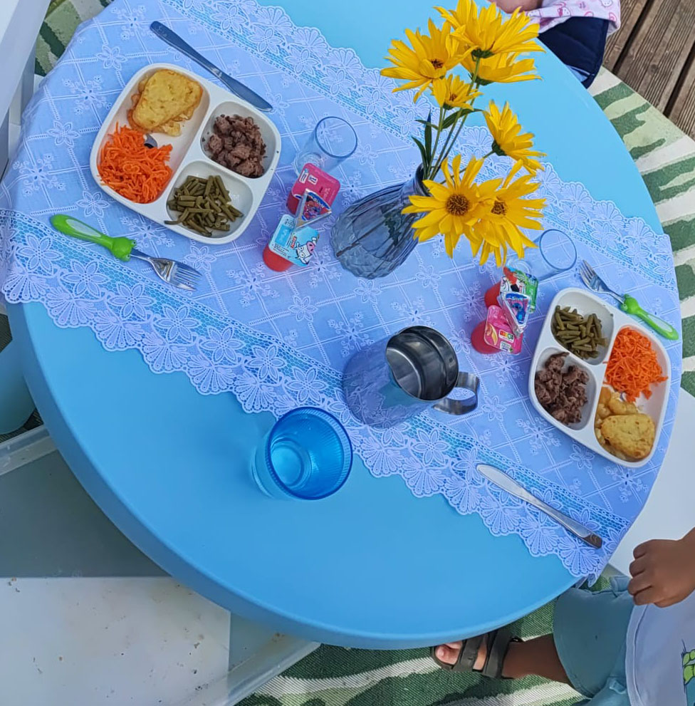 cantine-exterieure-tournesols-sarahpoppins Table de la cantine extérieure — tournesols et nappe dentelle, moment de repas soigné chez Sarah Poppins assistante maternelle