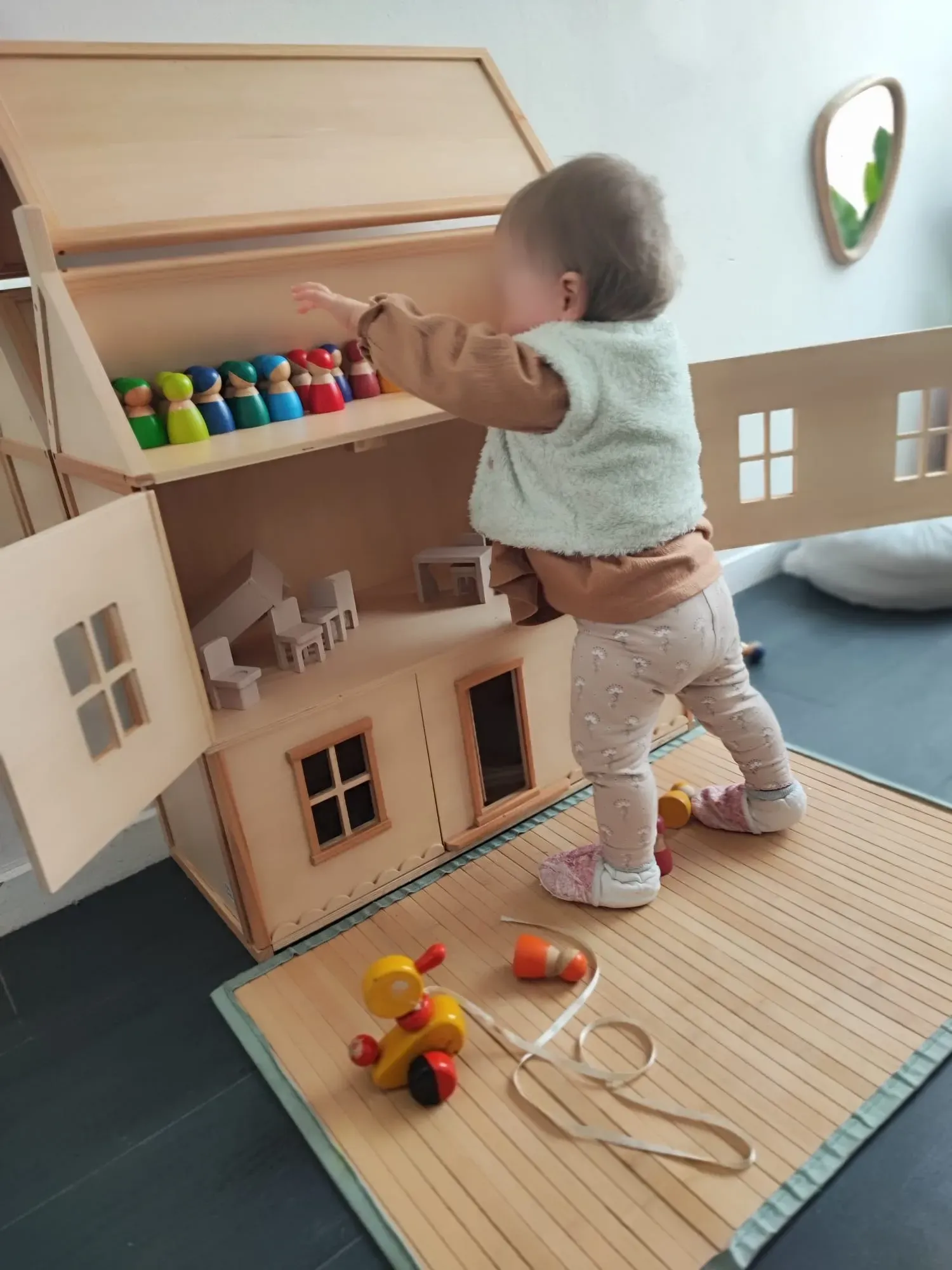 Bébé en pleine exploration de la maison de poupées — jeu libre et motricité, pédagogie Pikler Montessori chez Sarah Poppins